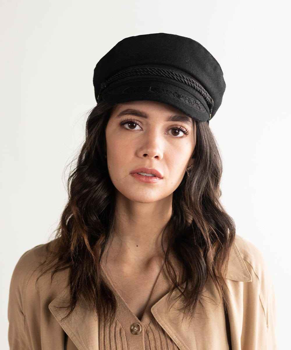 Woman wearing a black lieutenant  cap and a beige jacket against a plain background #color_black