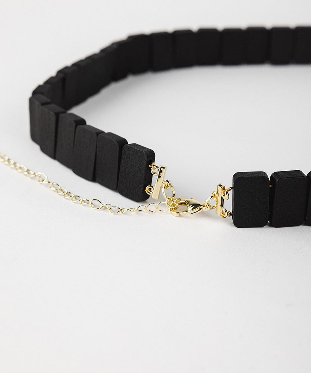 A black wooden beaded band on a plain background #color_black