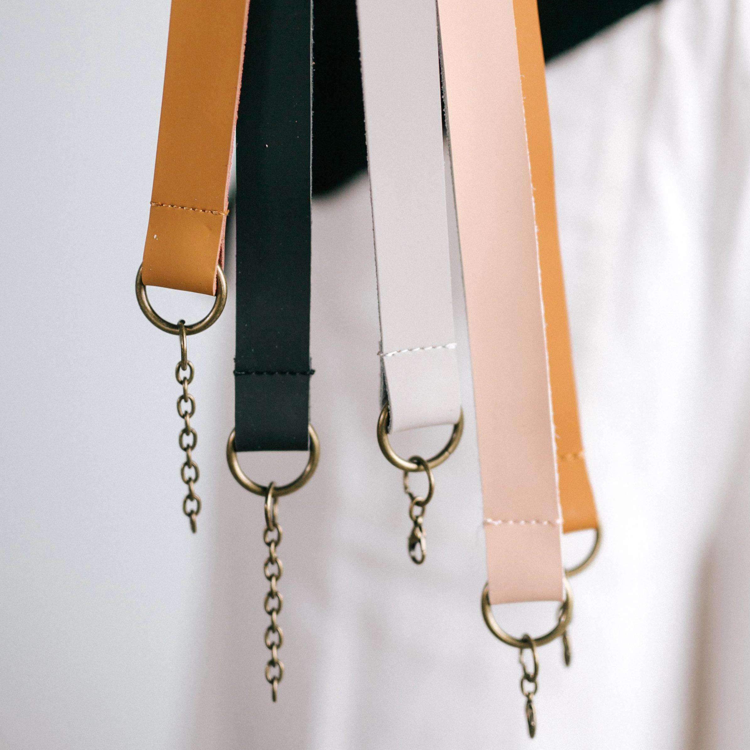 Nude, black, camel, cognac and stone colored leather adjustable chain bands against a plain background