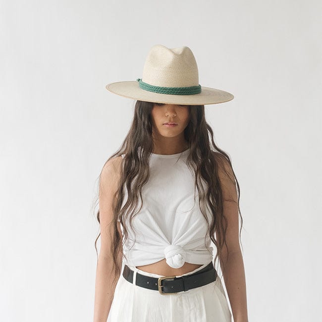 Woman wearing a cream hat with a fern colored thick rope hat band, a white top and white pants against a plain background #color_fern
