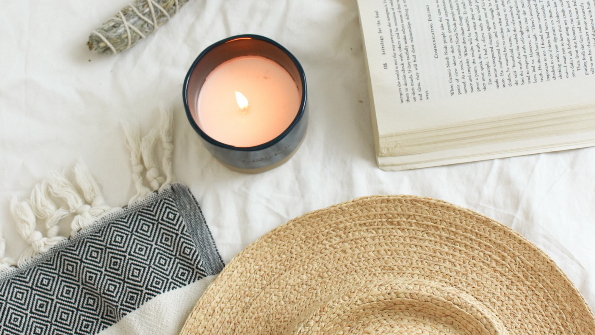 candle with book and candle laid out on white sheet