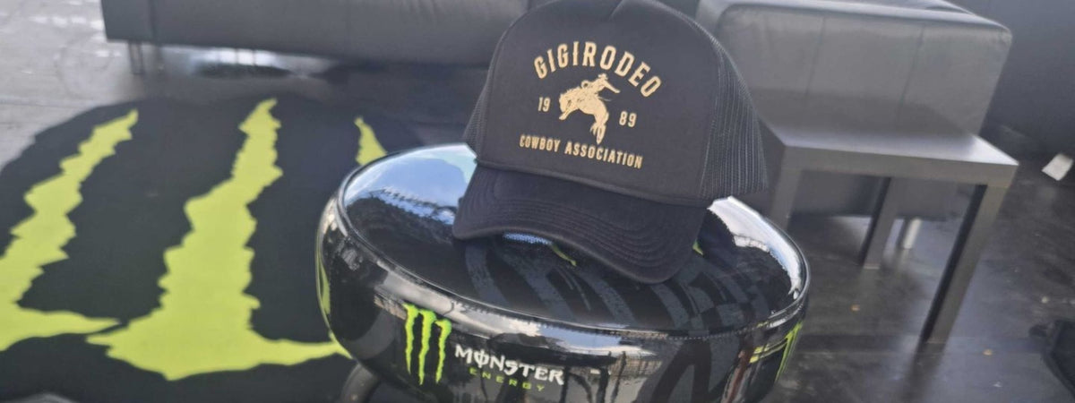 Black cap with 'Gigi Rodeo' branding on a black and yellow Monster Energy product at a custom hat bar event.