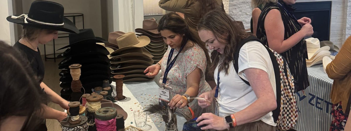People interacting with a display of hats and items at a custom hat bar event.
