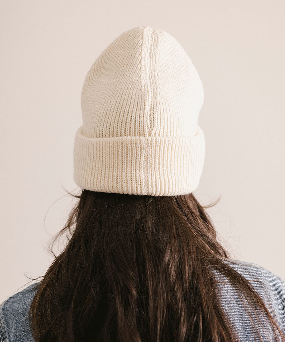 Person wearing a cream knit beanie against a plain background #color_off white