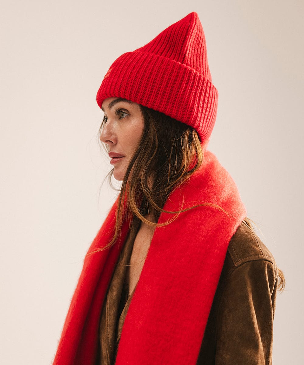 Person wearing a red beanie and scarf against a plain background #color_red