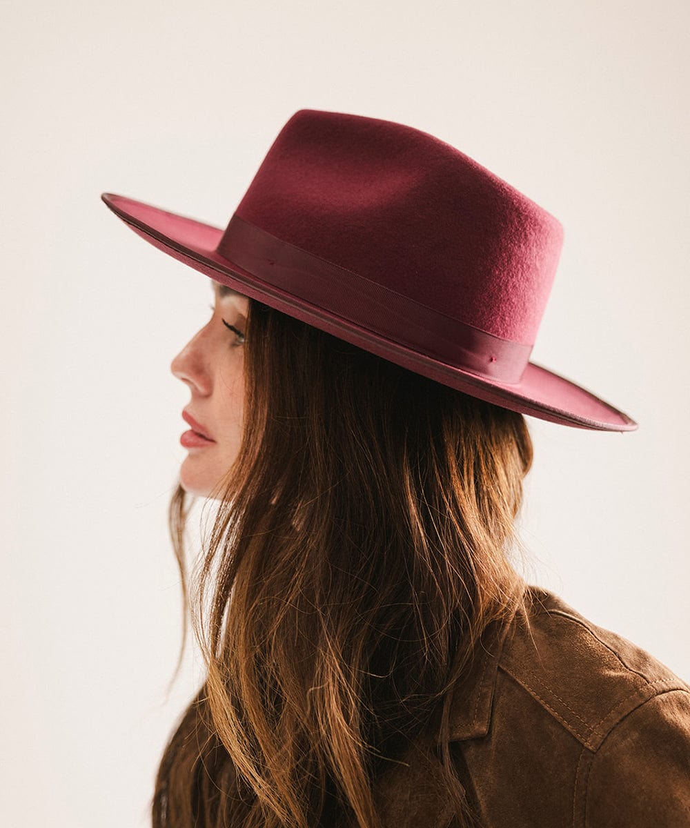 Woman wearing a maroon hat and brown jacket against a plain background #color_merlot
