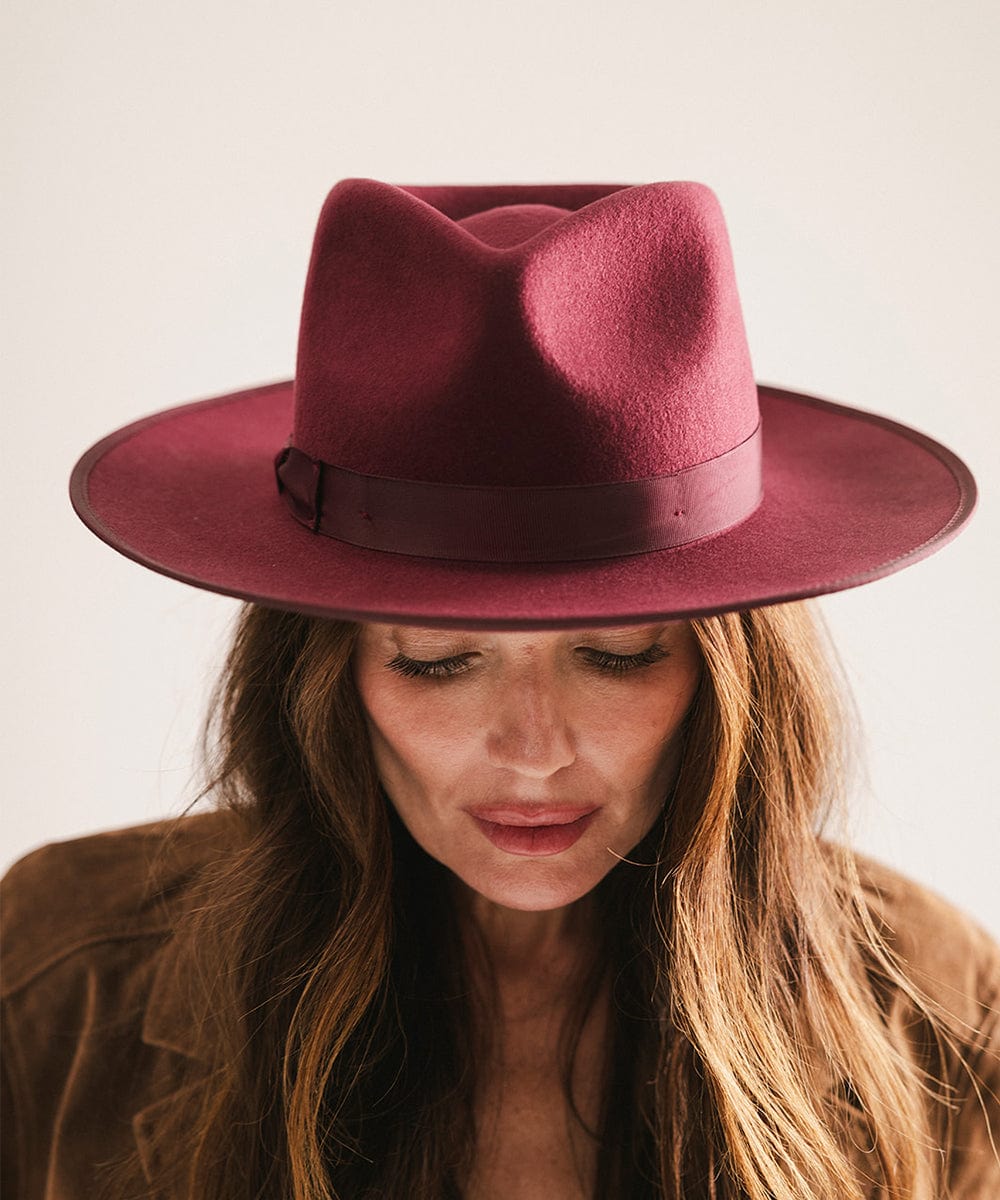 Person wearing a maroon fedora hat against a plain background #color_merlot