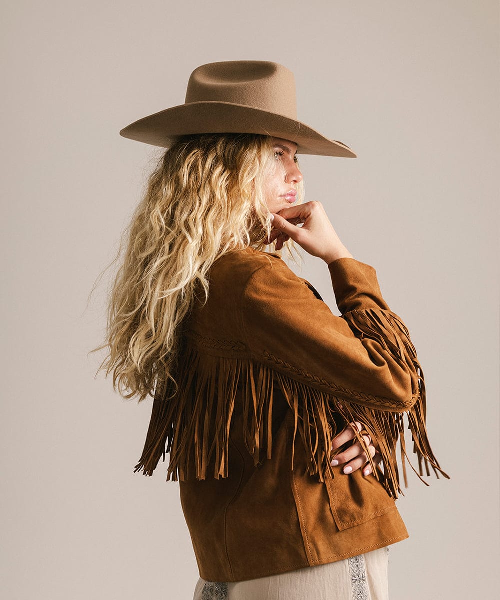 Woman wearing a brown fringed jacket and brown hat against a plain background #color_brown