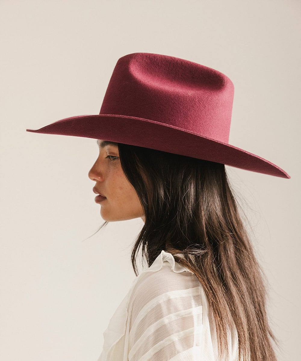Woman wearing a maroon hat against a plain background #color_merlot