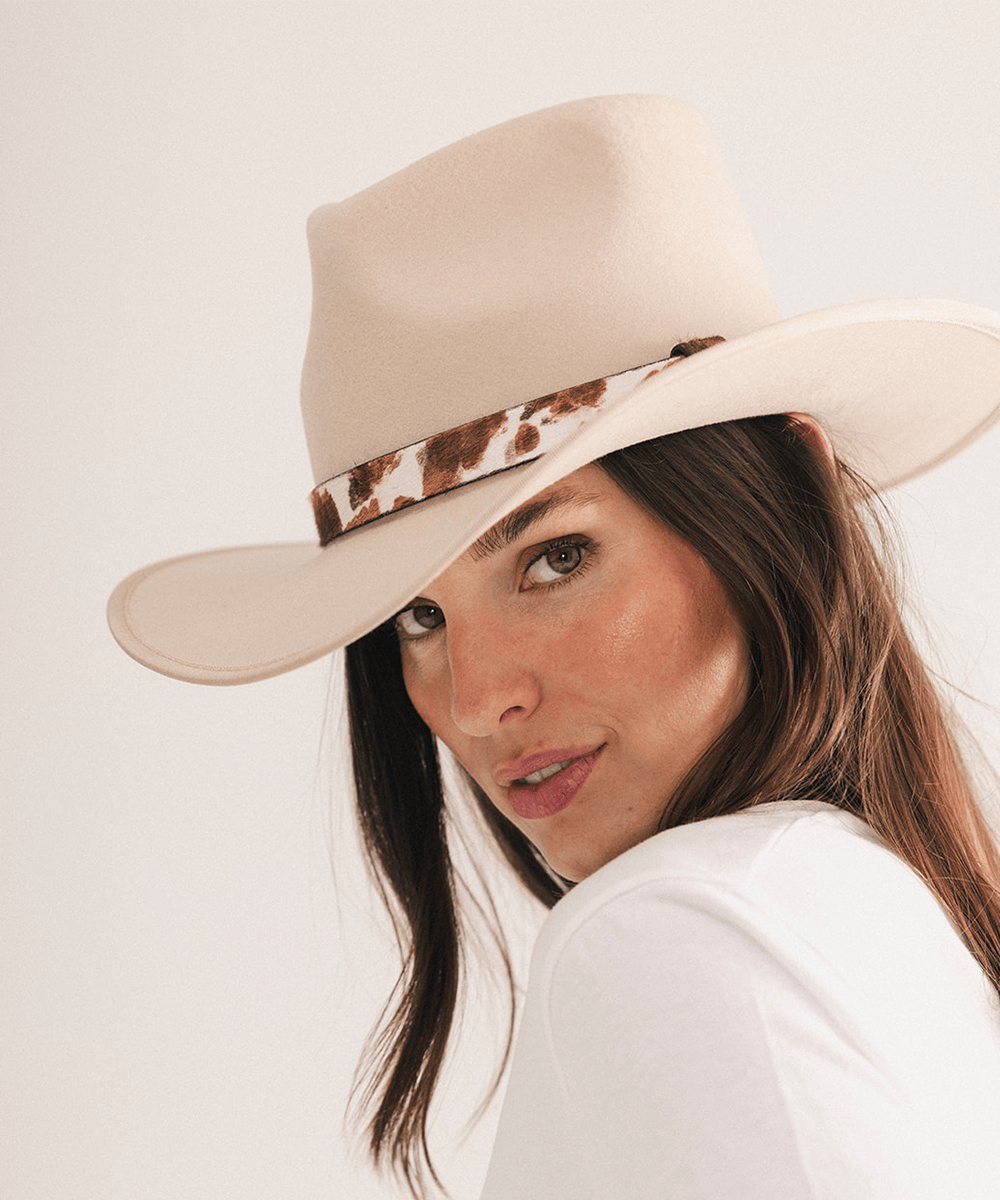 Woman wearing a beige cowboy hat with a cowhide decorative band on a white background #color_brown