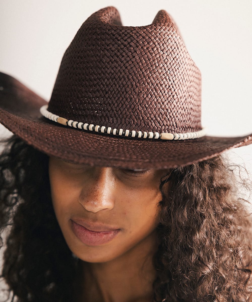 Woman wearing a brown cowboy hat in a plain background #color_brown-white