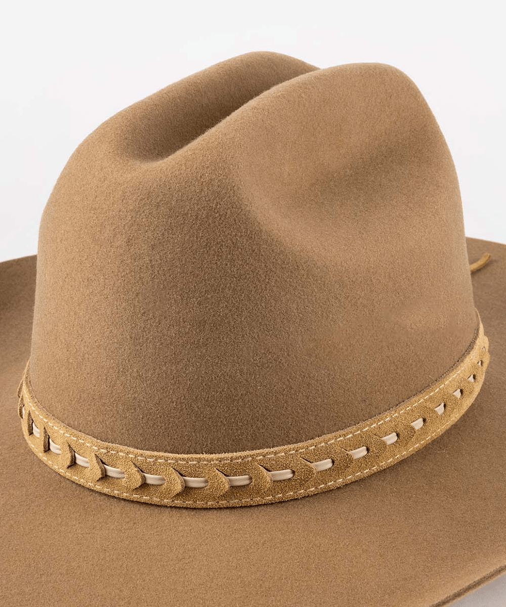 A close-up of a brown felt cowboy hat with a tan leather band featuring decorative stitching and woven details, set against a plain white background #color_camel