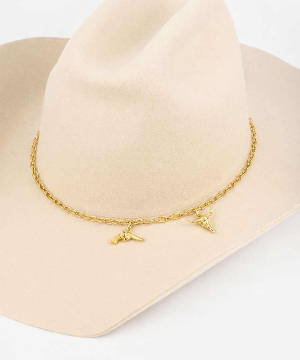 Gold necklace with charms on a beige cowboy hat against a white background #color_gold