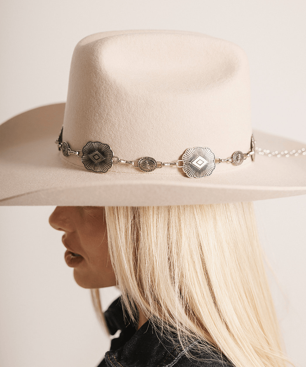 Woman wearing a cream hat with a silver western concho band against a plain background #color_silver