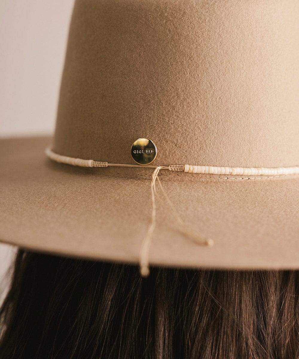 Close-up of a brown hat with a brand logo on a neutral background #color_natural fossil