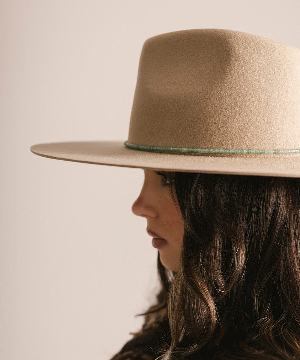 Person wearing a beige hat with a green band on a plain background #color_green jade
