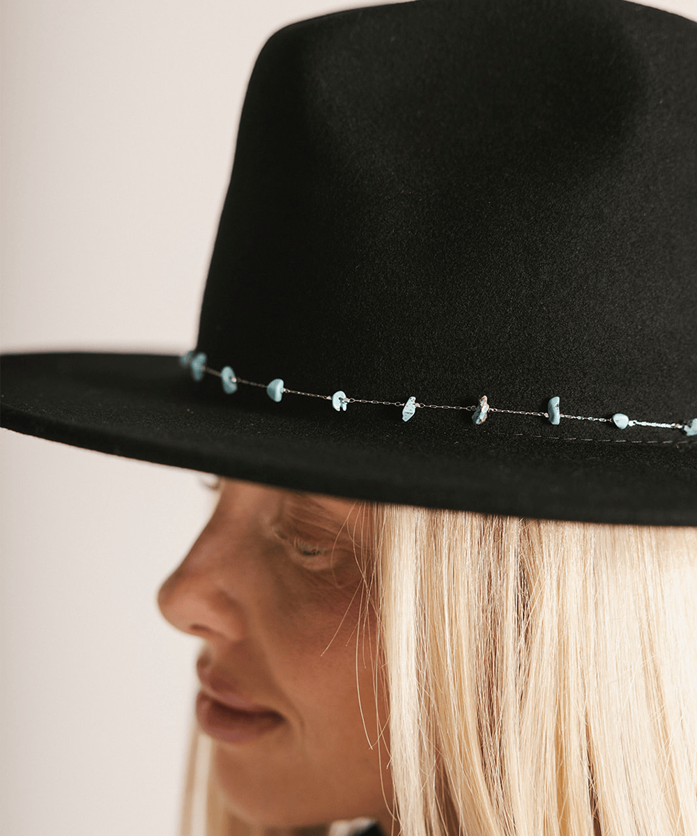 Close-up of a person wearing a black hat with decorative elements on a white background #color_silver