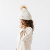 Gigi Pip beanies for kids - Milo Beanie - soft knit ribbers kid's beanie featuring a fold up brim with a rose gold Gigi Pip logo pin on the side of the fold and a pom pom on the center of the crown [oatmeal]