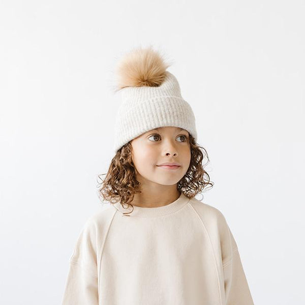 Gigi Pip beanies for kids - Milo Beanie - soft knit ribbers kid's beanie featuring a fold up brim with a rose gold Gigi Pip logo pin on the side of the fold and a pom pom on the center of the crown [oatmeal]