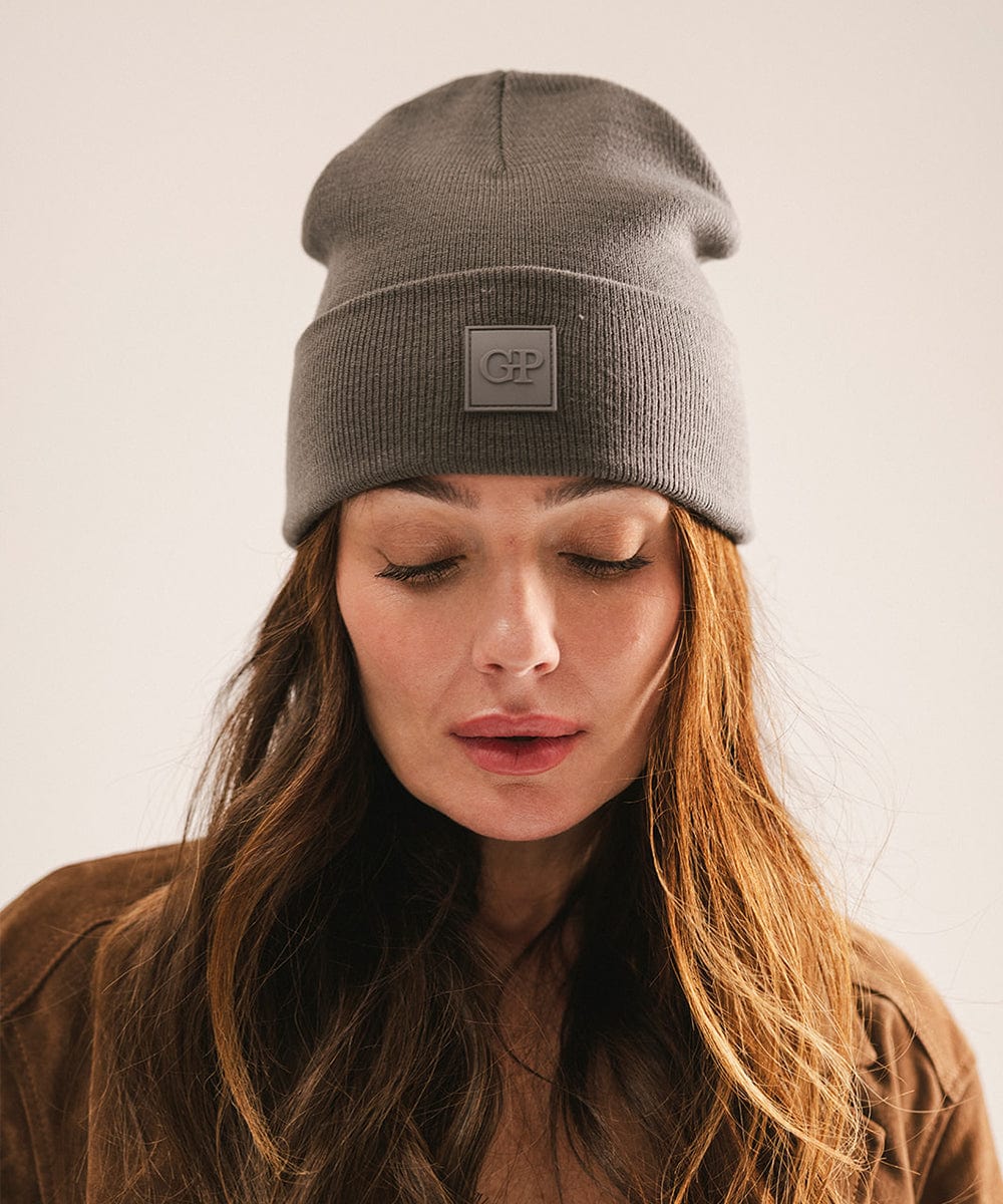 Woman wearing a gray beanie with a logo on a plain background #color_grey