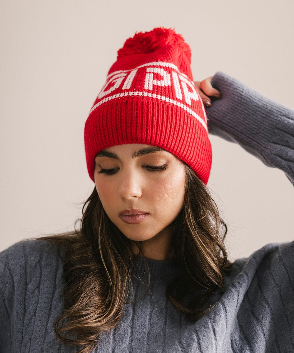 Woman wearing a red beanie with white text against a neutral background #color_ruby red