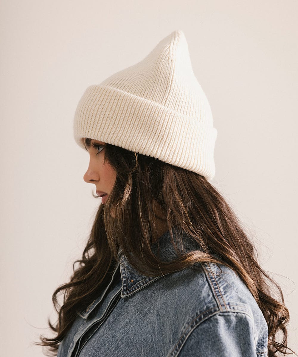 Person wearing a beige beanie and denim jacket against a plain background #color_off white