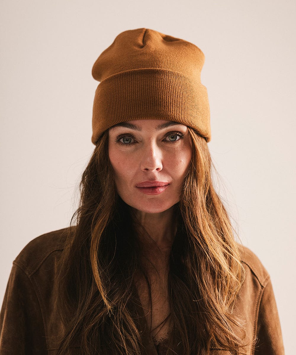 Woman wearing a brown beanie and jacket against a plain background #color_cocoa