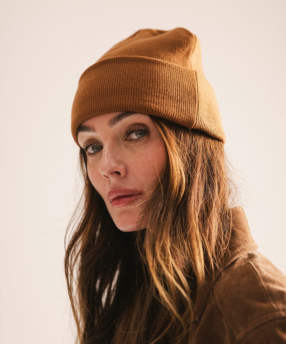 Woman wearing a brown beanie and coat against a plain background #color_cocoa