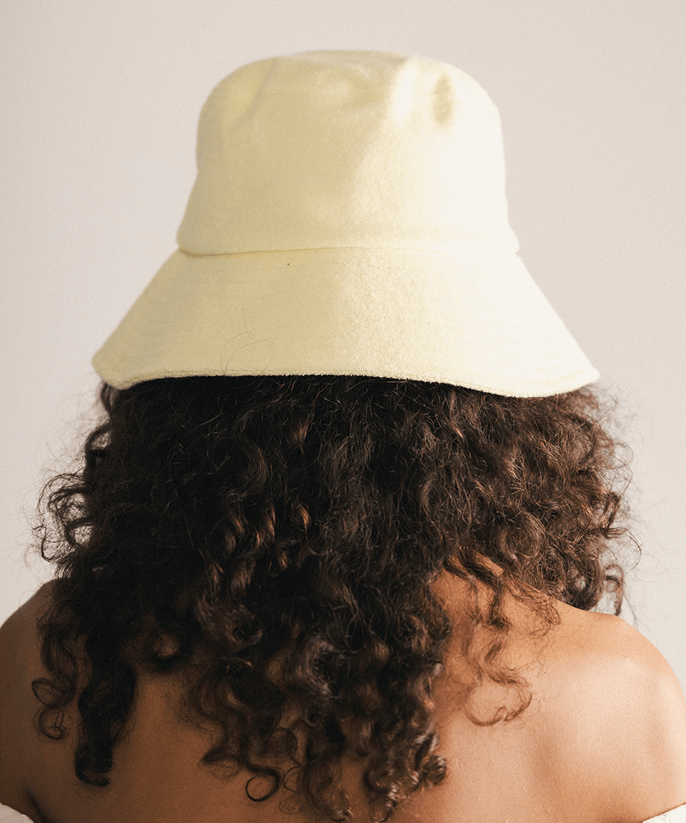Woman wearing a yellow bucket hat against a plain background #color_ butter yellow