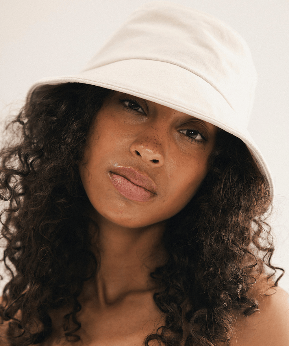 Woman wearing a cream bucket hat with a plain background #color_cream