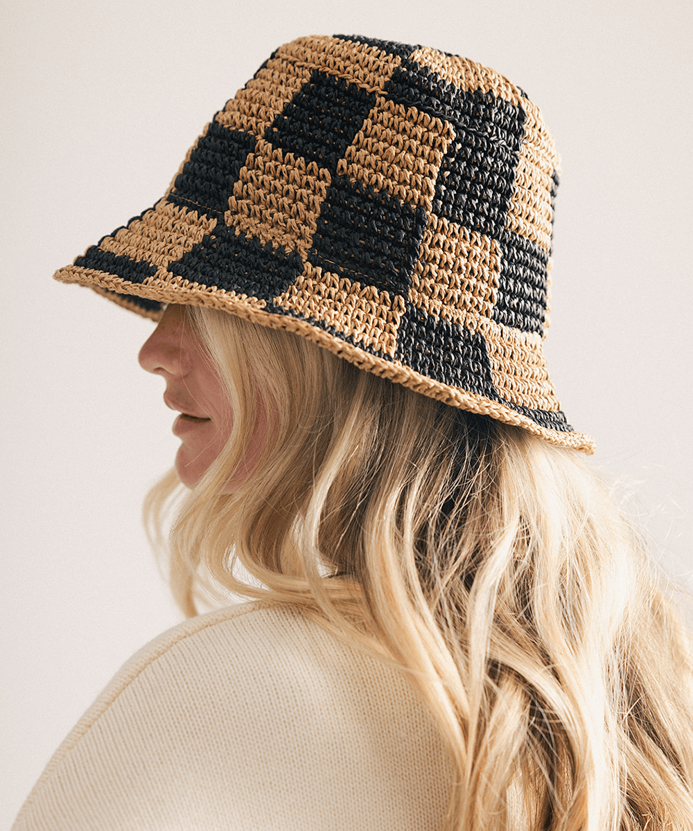Woman wearing a black checkered crochet packable bucket hat made from paper straw, displayed against a white background. #color_black check
