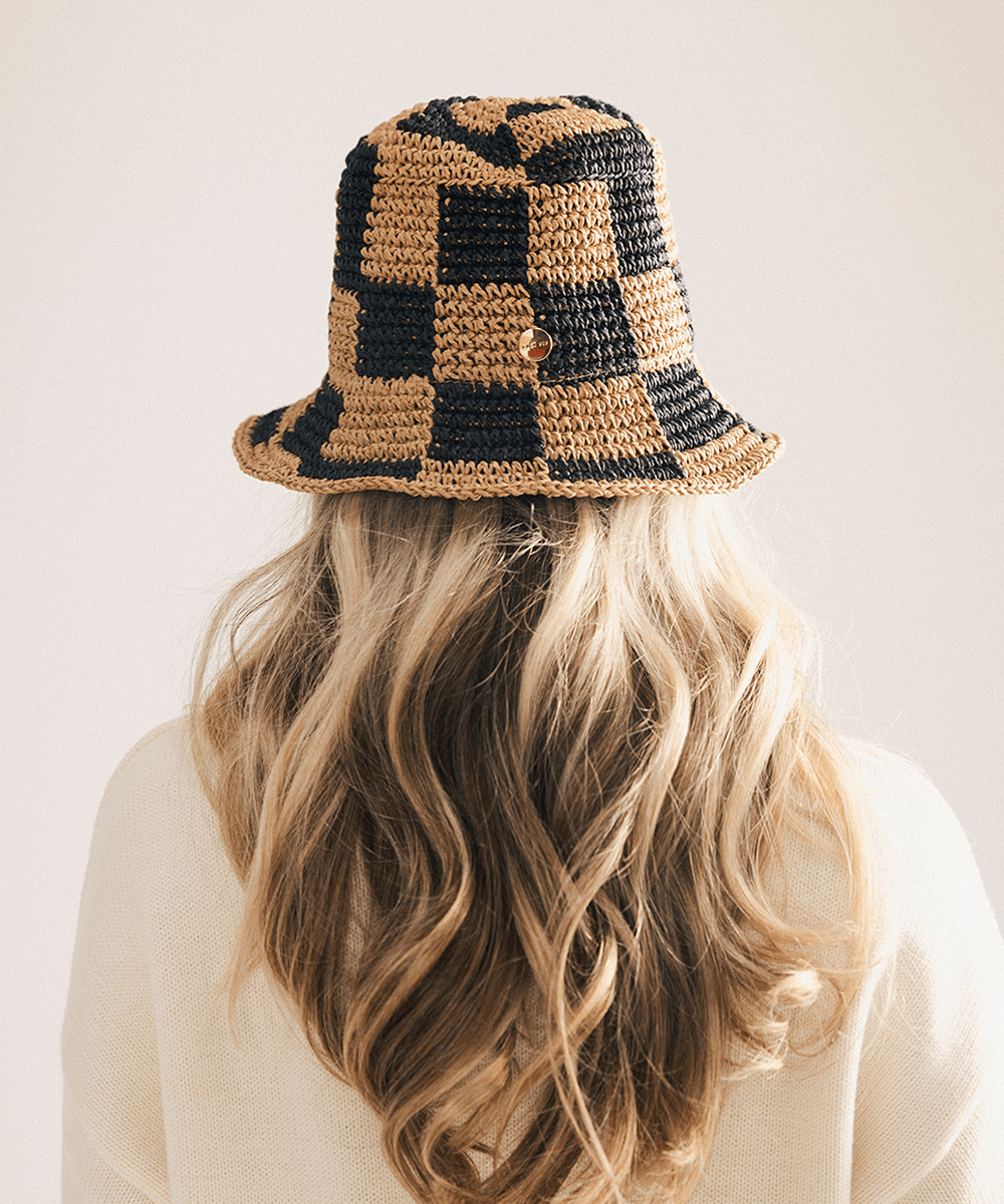 Woman wearing a black checkered crochet packable bucket hat made from paper straw, displayed against a white background. #color_black check