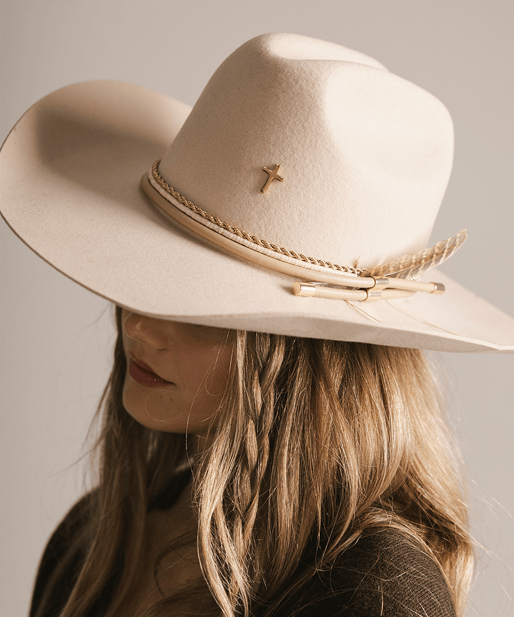 Beige cowboy hat with decorative band and cross on a neutral background #color_gold