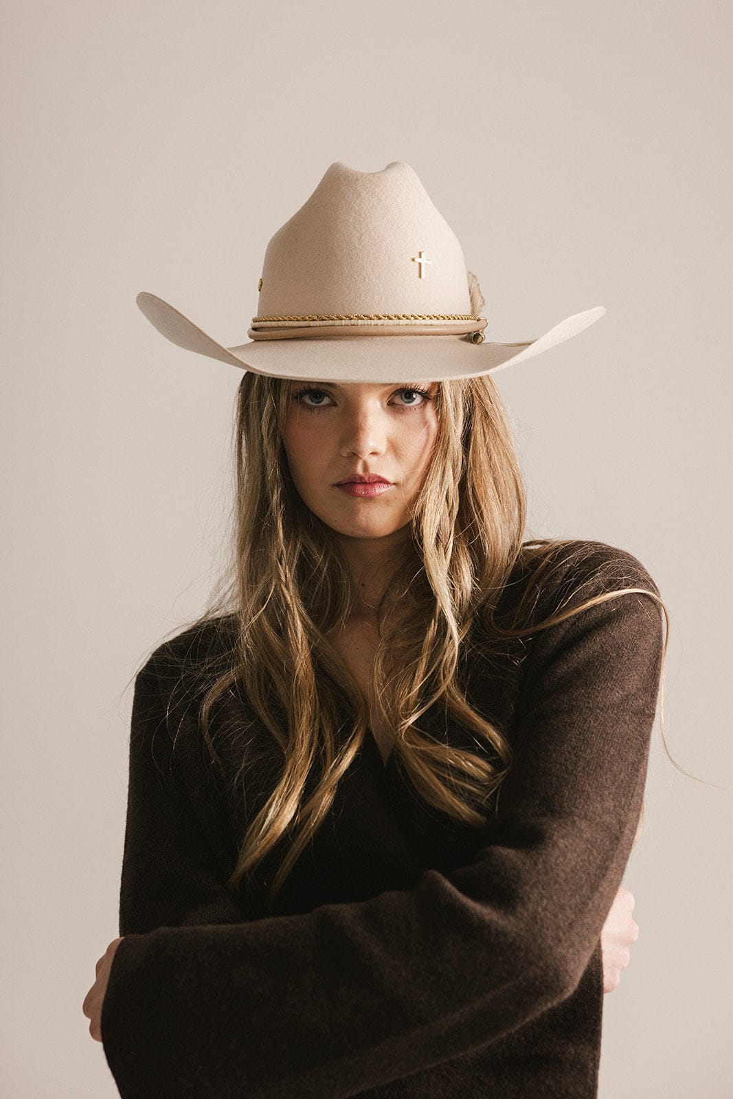 Woman wearing a beige cowboy hat against a plain background #color_gold