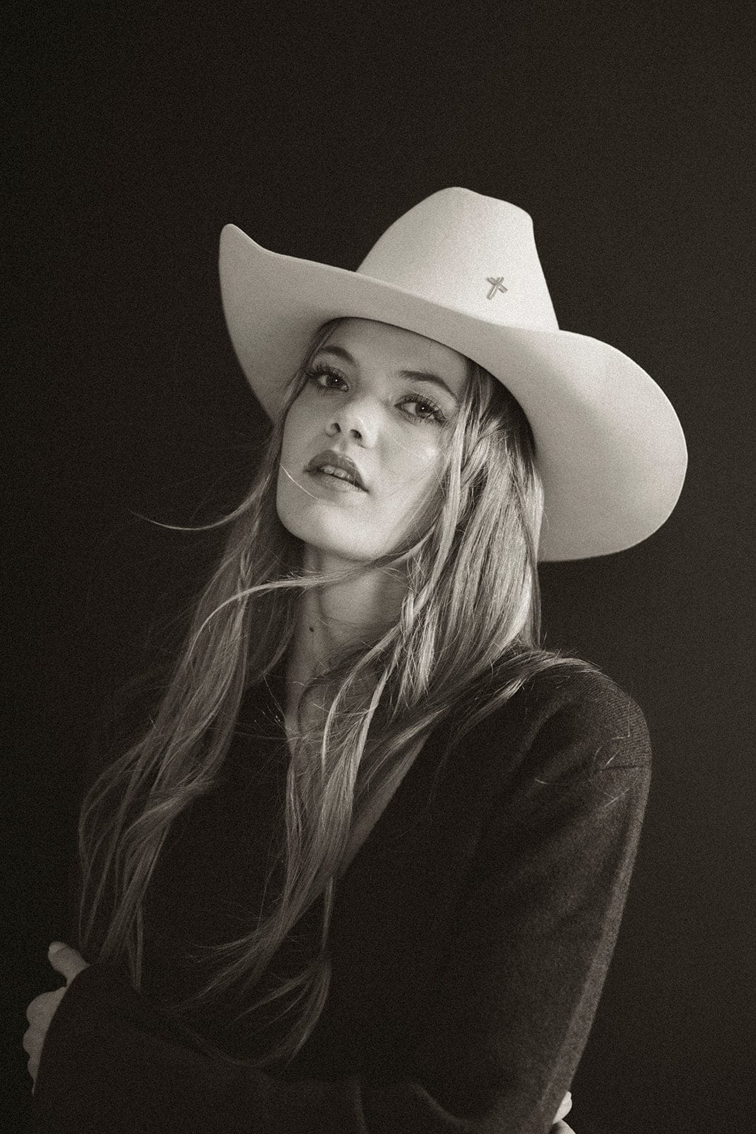 Black and white portrait of a woman wearing a cowboy hat against a dark background #color_silver