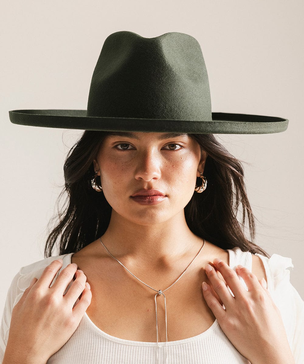 Woman wearing a dark green wide-brimmed hat against a neutral background #color_dark green