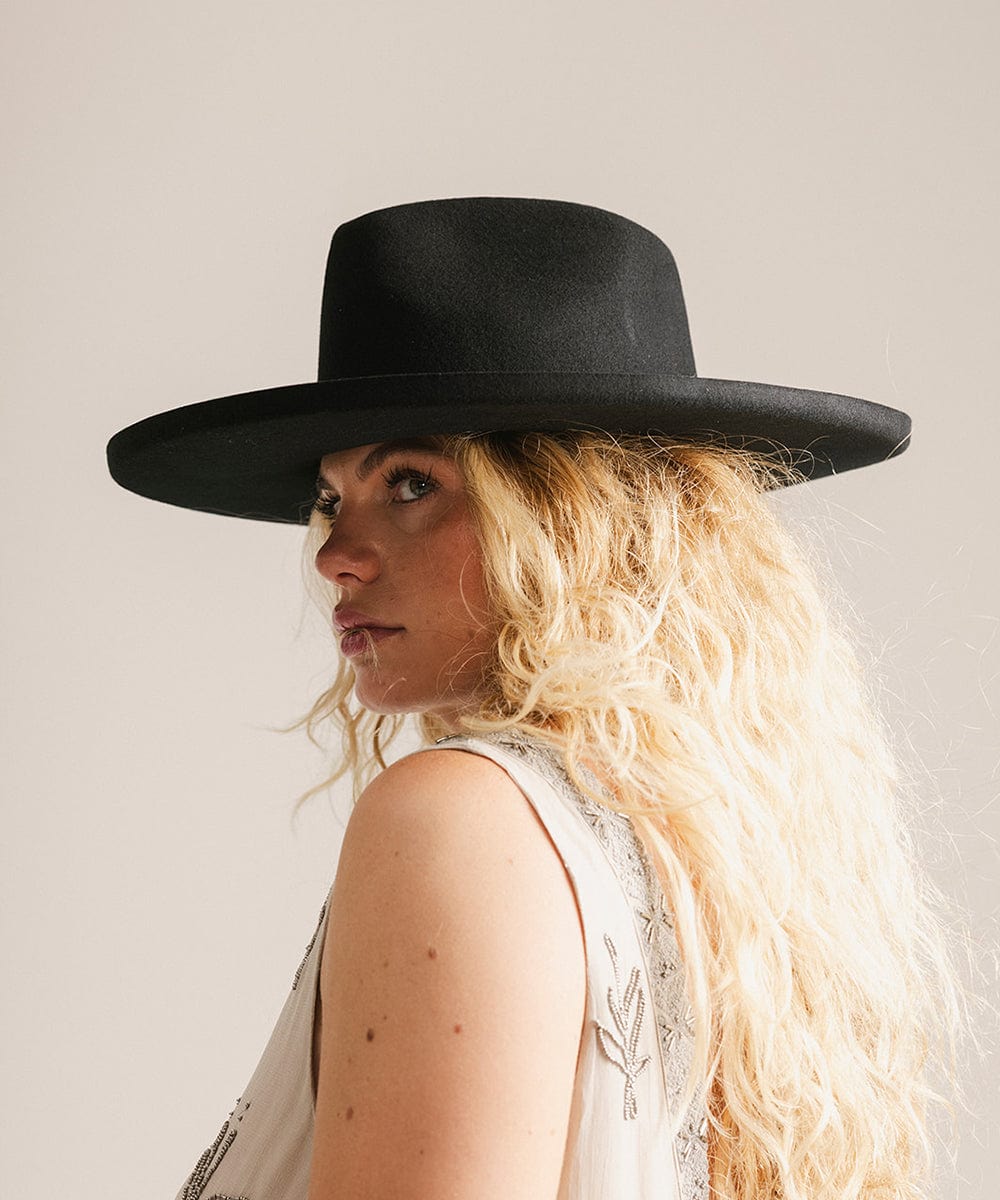 Woman wearing a black hat against a plain background #color_black