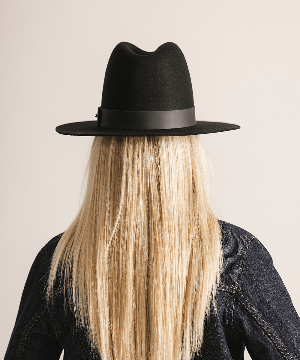Woman wearing a black tall fedora hat against a plain background #color_black
