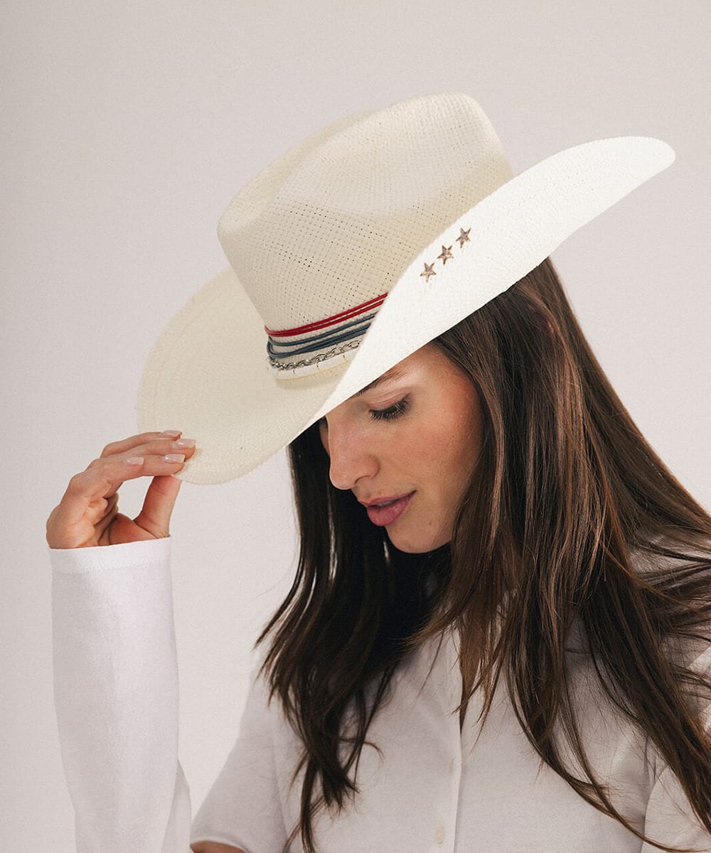 Woman wearing a cowboy hat with decorative bands and star pins in a plain background #color_natural white