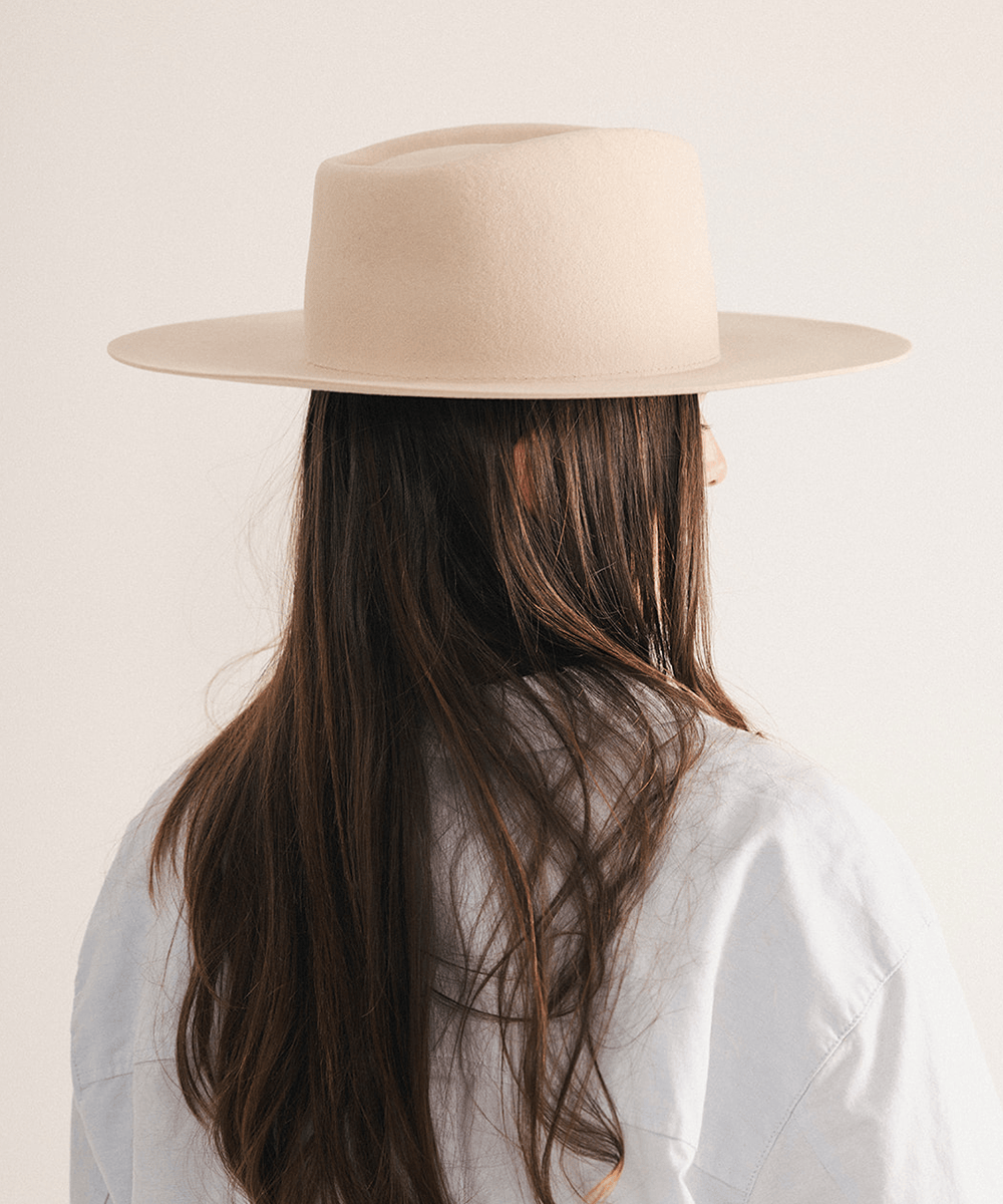 Woman wearing a wide brim felt hat on a white background #color_cream