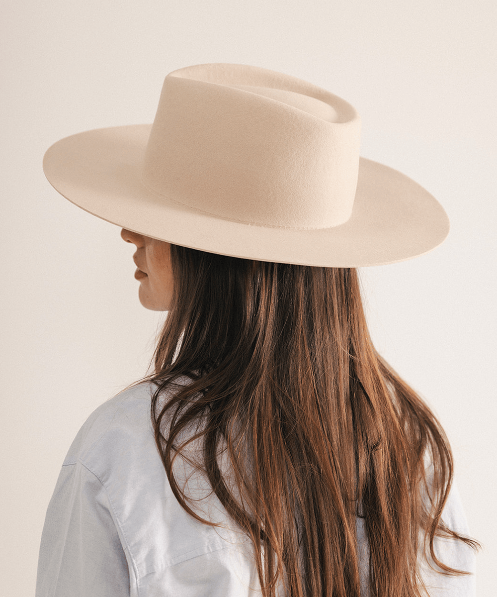 Woman wearing a wide brim felt hat on a white background #color_cream