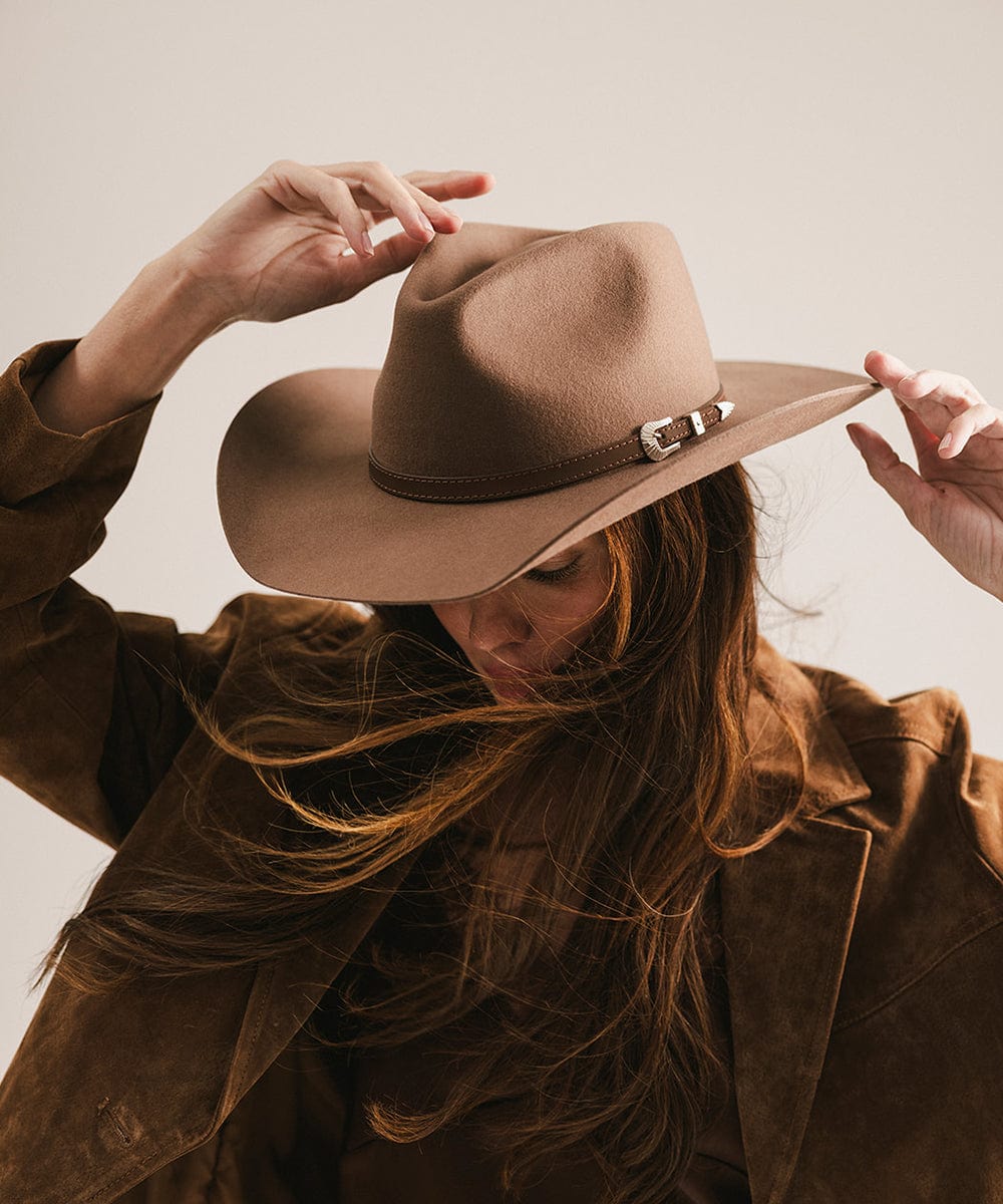Person wearing a brown hat and coat against a neutral background #color_chocolate
