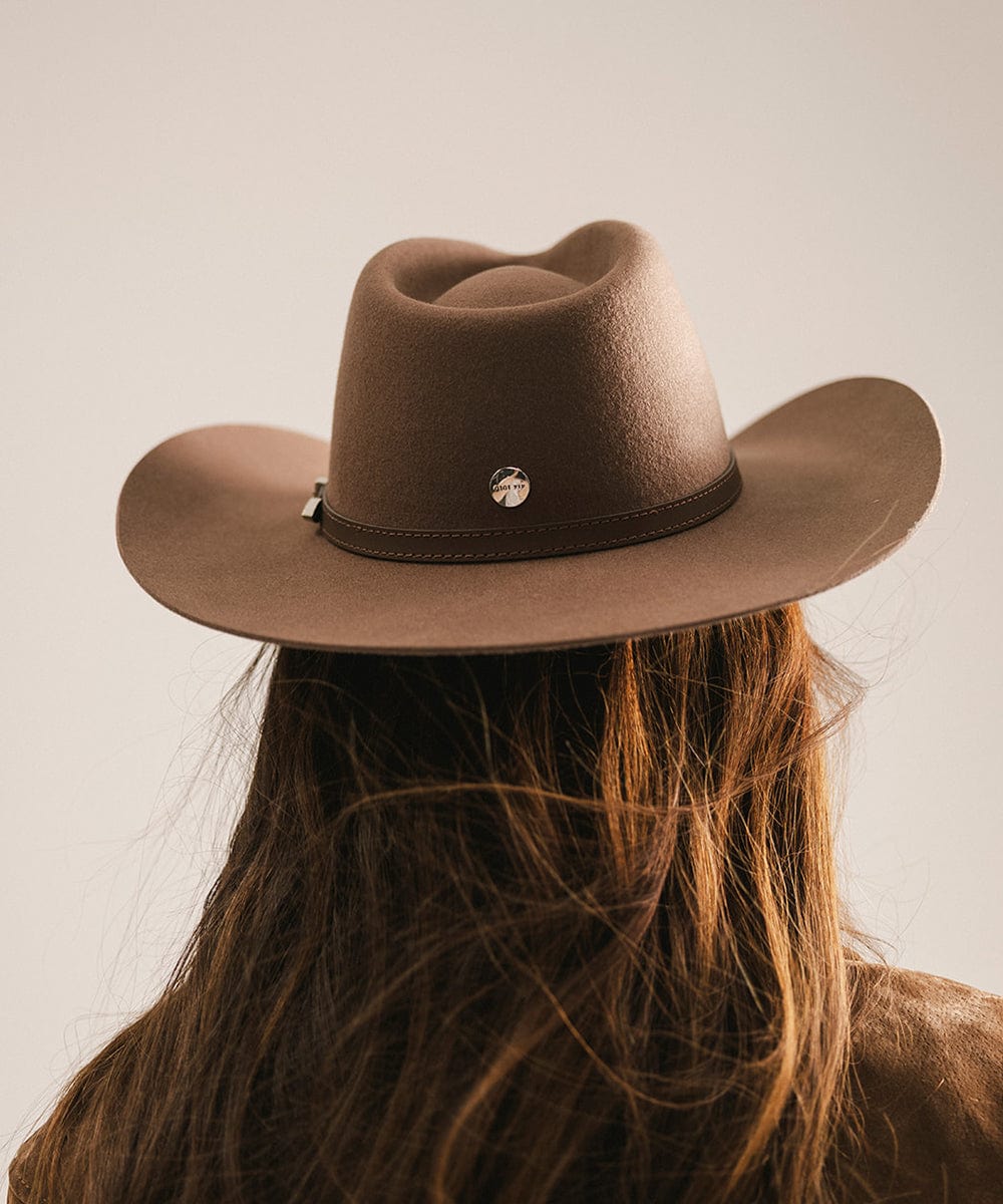Brown cowboy hat worn by a person with long hair on a plain background #color_chocolate