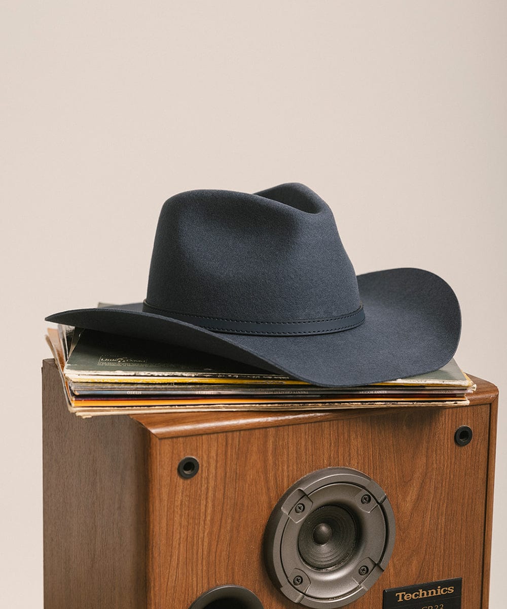 Black cowboy hat on top of a wooden Technics record player. #color_vintage blue