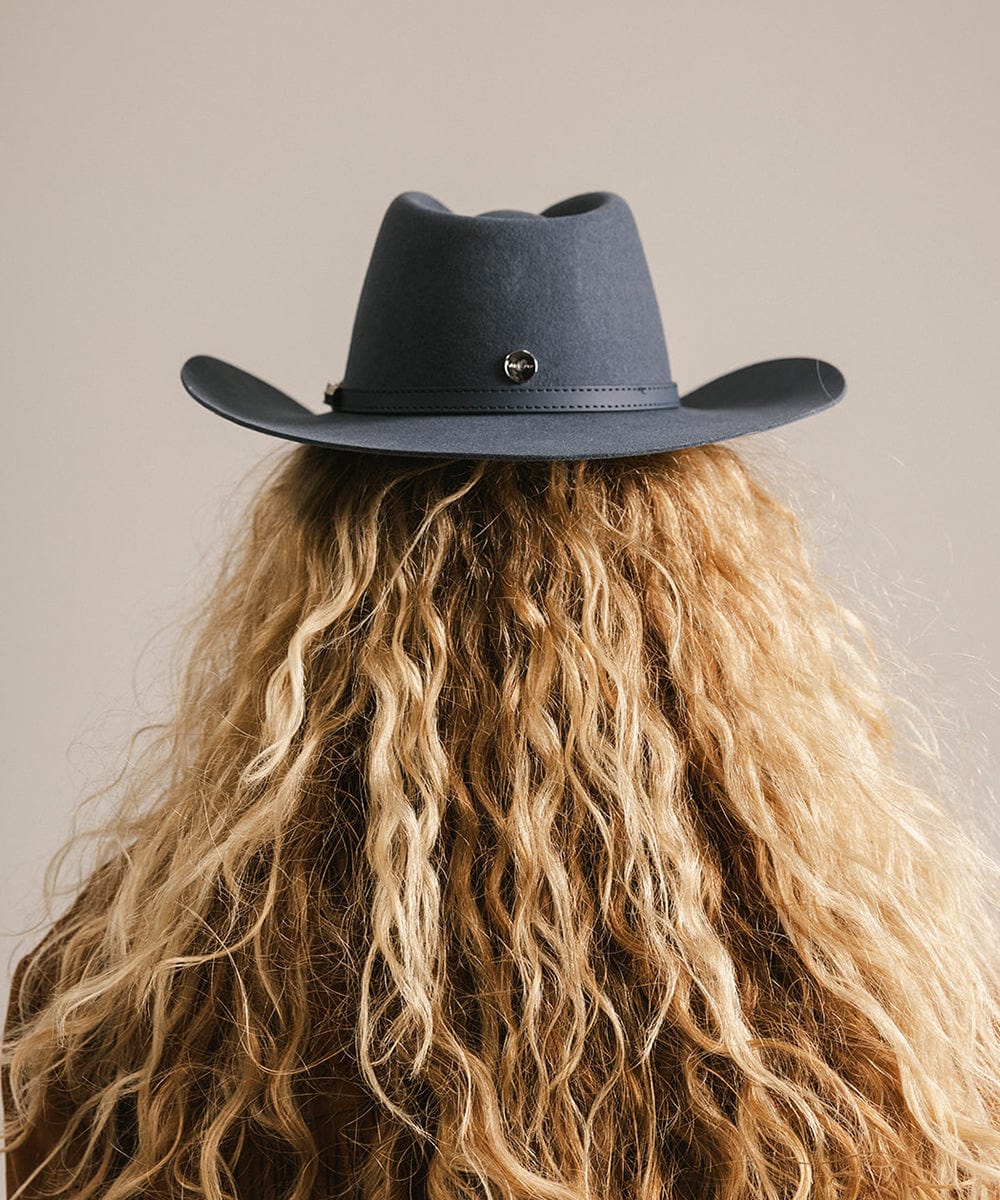 Person wearing a dark blue cowboy hat with a neutral background #color_vintage blue