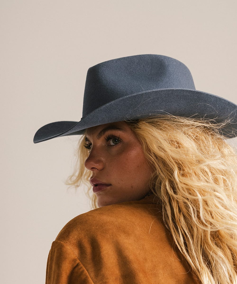 Woman wearing a blue fedora hat against a neutral background #color_vintage blue