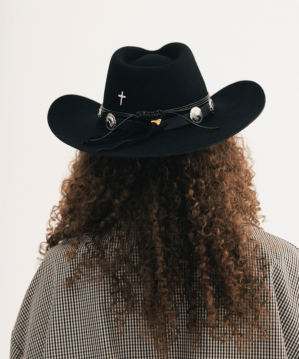 Woman wearing a black cowboy hat with a concho hat band and a plaid shirt #color_black