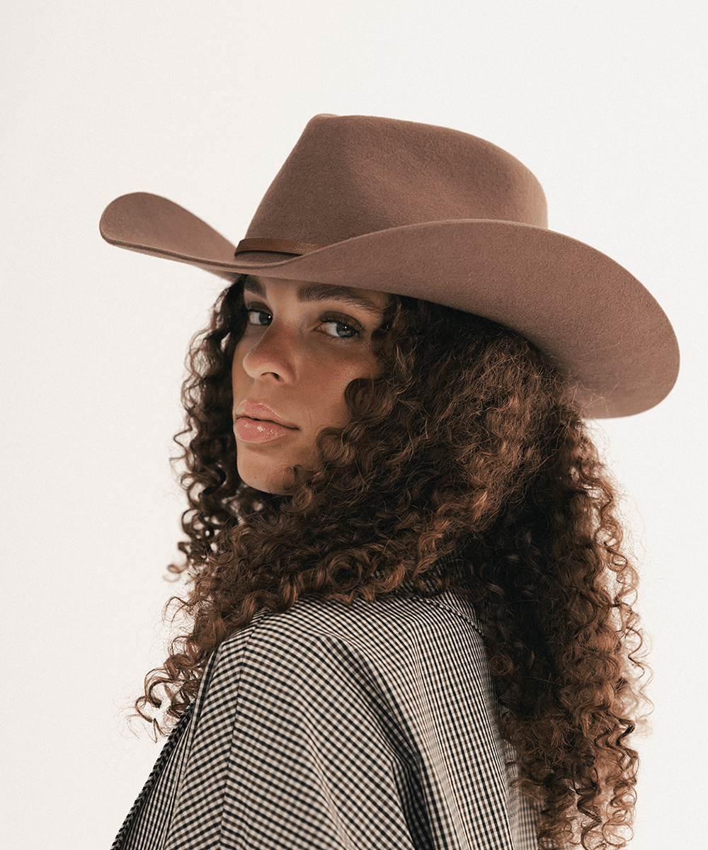 Woman wearing a brown cowboy hat with a brown hat band and a plaid shirt #color_chocolate