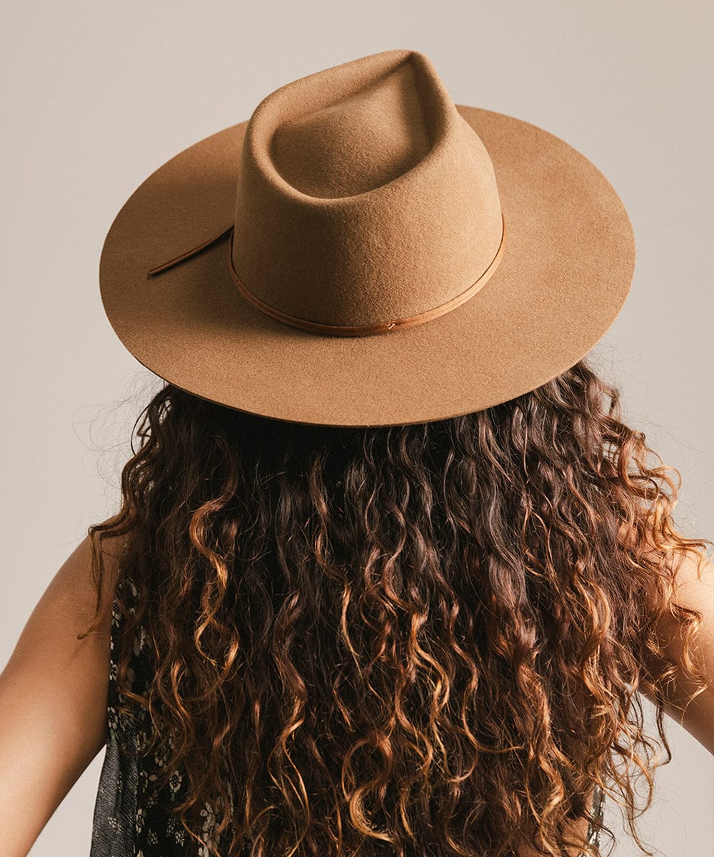 Person wearing a brown fedora hat with a neutral background #color_caramel