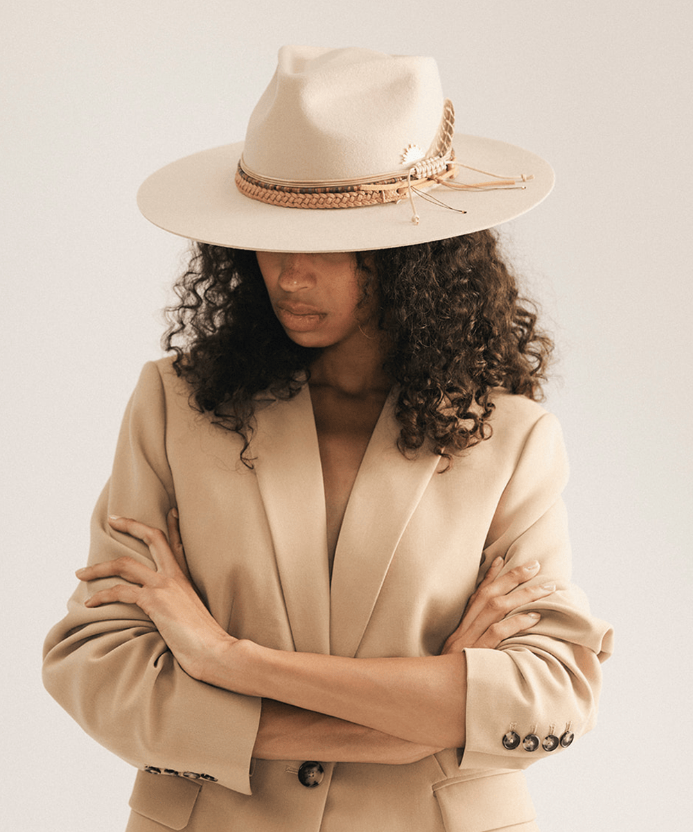 Woman wearing a beige cowboy hat with braided detail against a white background #color_tan